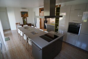 Eine moderne Küche mit einer zentralen Kochinsel, Edelstahlgeräten und einem Essbereich mit Stühlen.