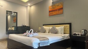 A neatly made bed with two swan-shaped towels, a bedside table with a kettle, and a painting on the wall. - Soaa Resort (Sirajganj)