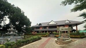 A multi-story building with a 'WELCOME TO Soraa Resort' sign, a stone fountain, and a paved walkway. - Soaa Resort (Sirajganj)