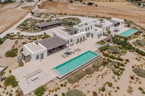 Eine moderne Villa mit Swimmingpool, Sitzgelegenheiten im Freien und einem angelegten Garten.