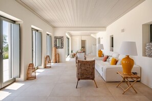 A spacious living area with a white sofa, wicker chairs, and a large lamp. - Amazing view of Naxos (X6W3+3G4 Paros, Greece)