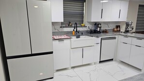 Une cuisine moderne avec des armoires blanches, un plan de travail en marbre et un lave-vaisselle encastré.