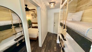 Een kamer met stapelbedden, een plafondventilator, een deur en een kleine plant.