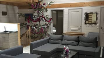 Una sala moderna con un sofá seccional, una mesa de centro, un reloj de pared y un árbol de Navidad decorado.