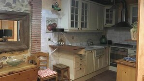 Une cuisine rustique avec des meubles en bois, une table à manger et un petit tabouret.