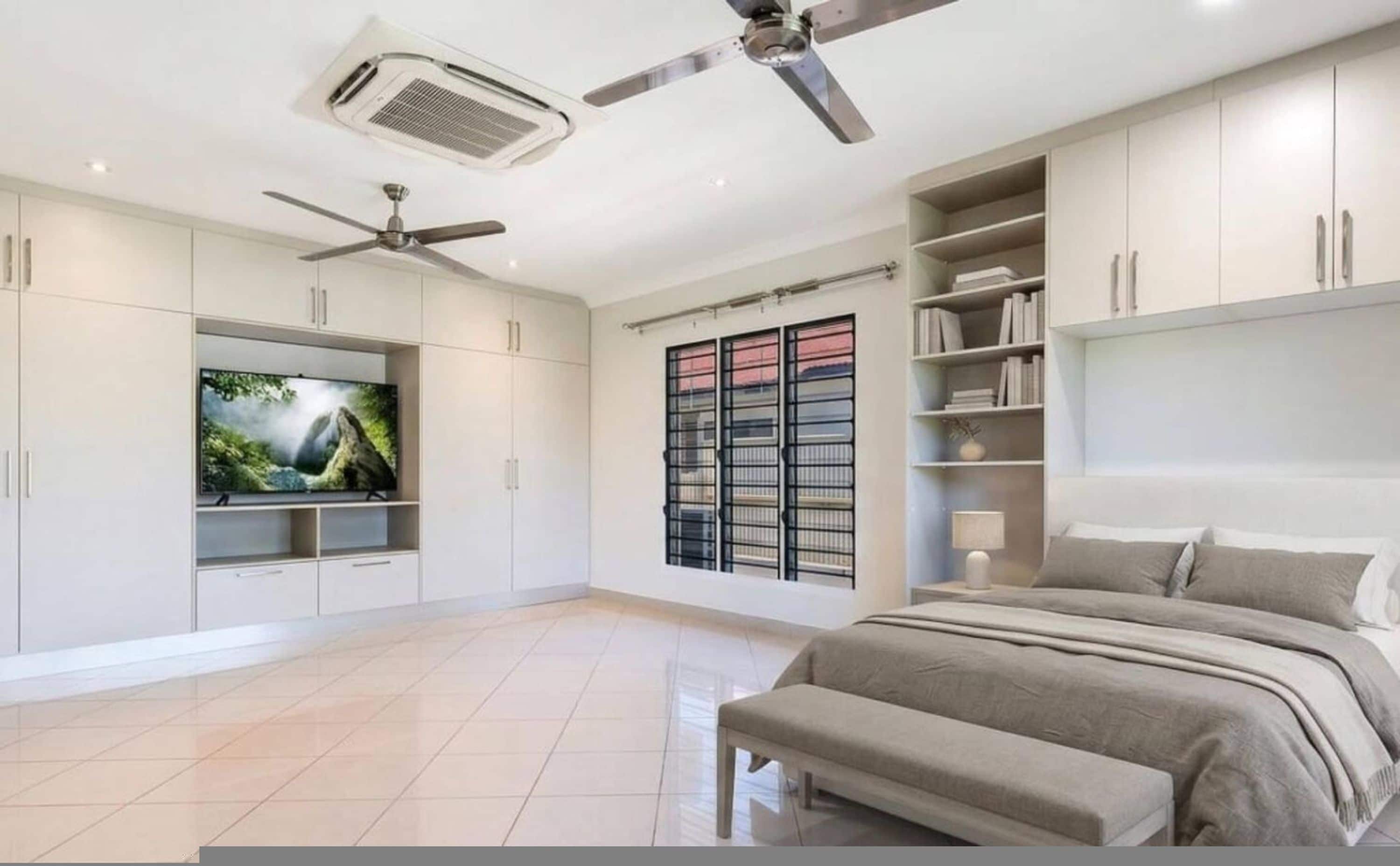 A bedroom with a bed, a TV, a ceiling fan, and built-in shelving.