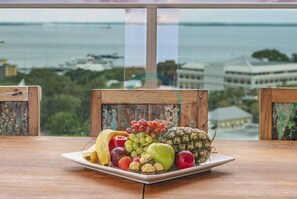A fruit platter on a table with a view of a body of water and buildings in the background. - Coastal Magnificence Pool Workspace Parking (Darwin)