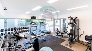 Une salle de sport équipée de tapis de course, d’haltères et d’appareils de musculation.