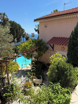 A pool with a pergola, surrounded by lush greenery and a view of the sea. - Small villa close to the sea with swimming pool and garden of eden. holiday/reunion (Vallauris)