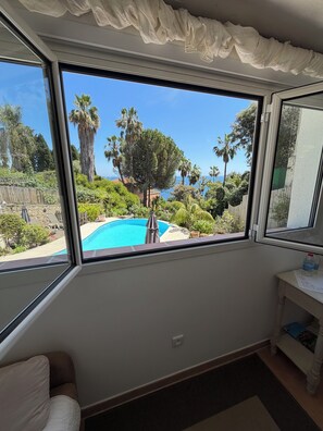 A room with a large window overlooking a swimming pool and lush greenery. - Small villa close to the sea with swimming pool and garden of eden. holiday/reunion (Vallauris)