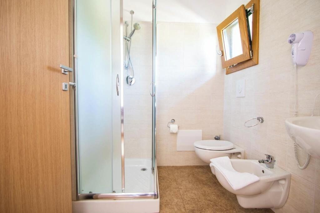 A bathroom with a glass-enclosed shower, a toilet, a bidet, and a sink.