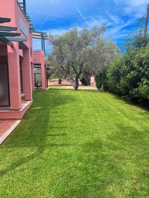 A well-maintained grassy area with a modern building featuring a pergola and outdoor seating.