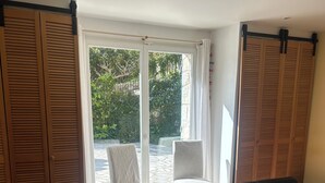 Een slaapkamer met een bed, een stoel en een schuifdeur naar een buitenruimte.