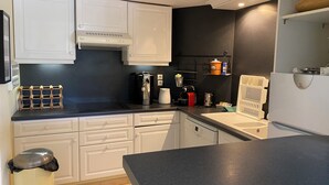 Eine moderne Küche mit weißen Schränken, einer schwarzen Arbeitsplatte, einer Kaffeemaschine und einem eingebauten Backofen.