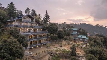 Un hotel de varios pisos con balcones, un patio interior y árboles circundantes.