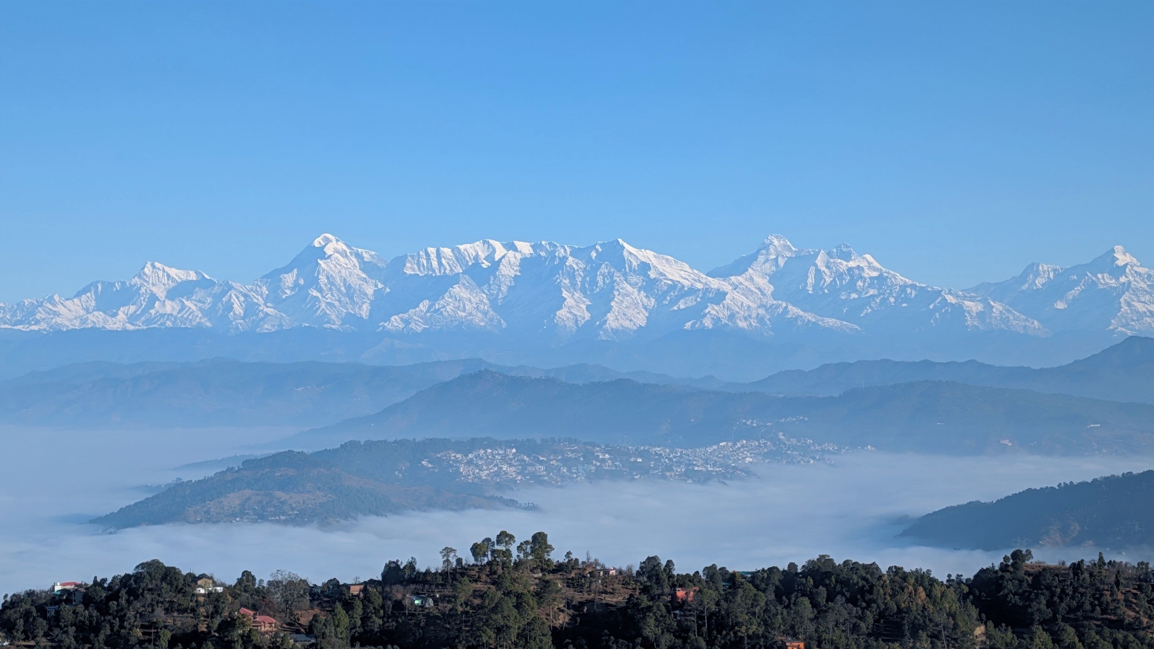 A mountainous landscape with snow-capped peaks and a valley with scattered buildings.