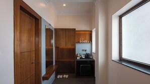 A narrow hallway with wooden cabinets, a small kitchenette, and a window.