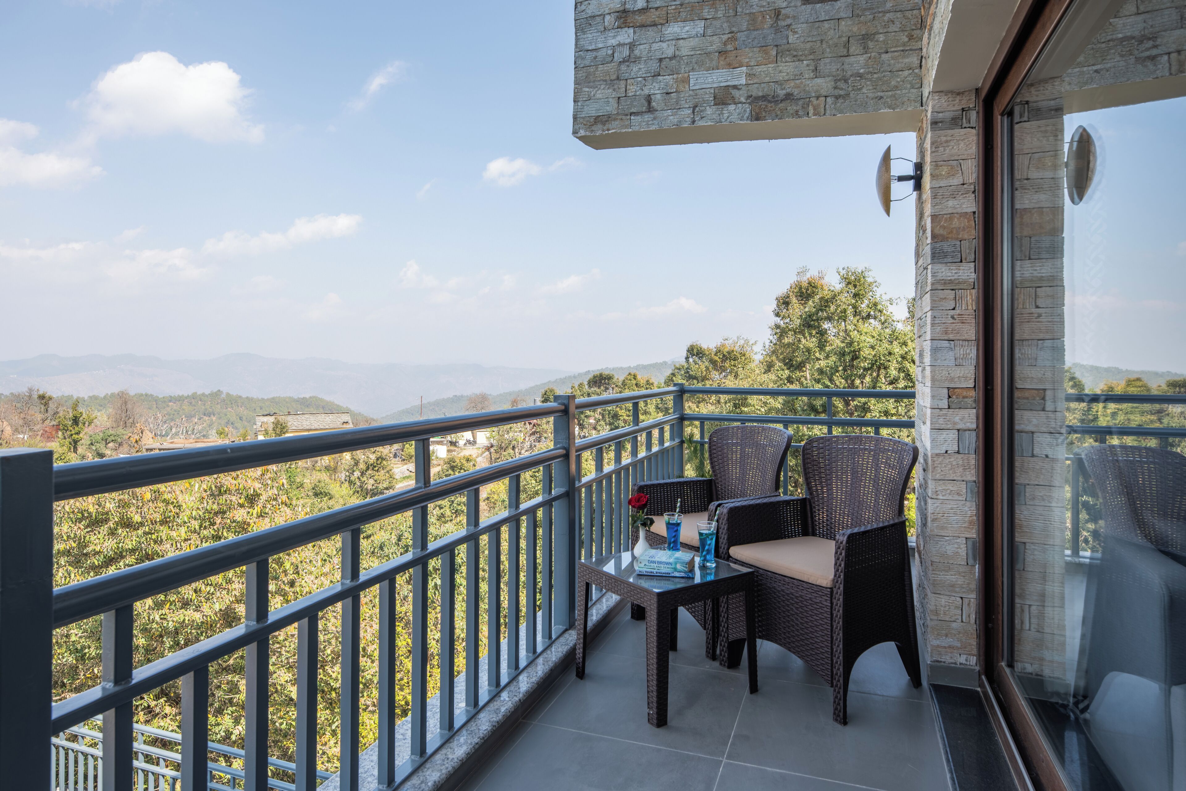 A balcony with wicker furniture, a glass table, and a book titled 'All Your Best Friends Are Mine.'