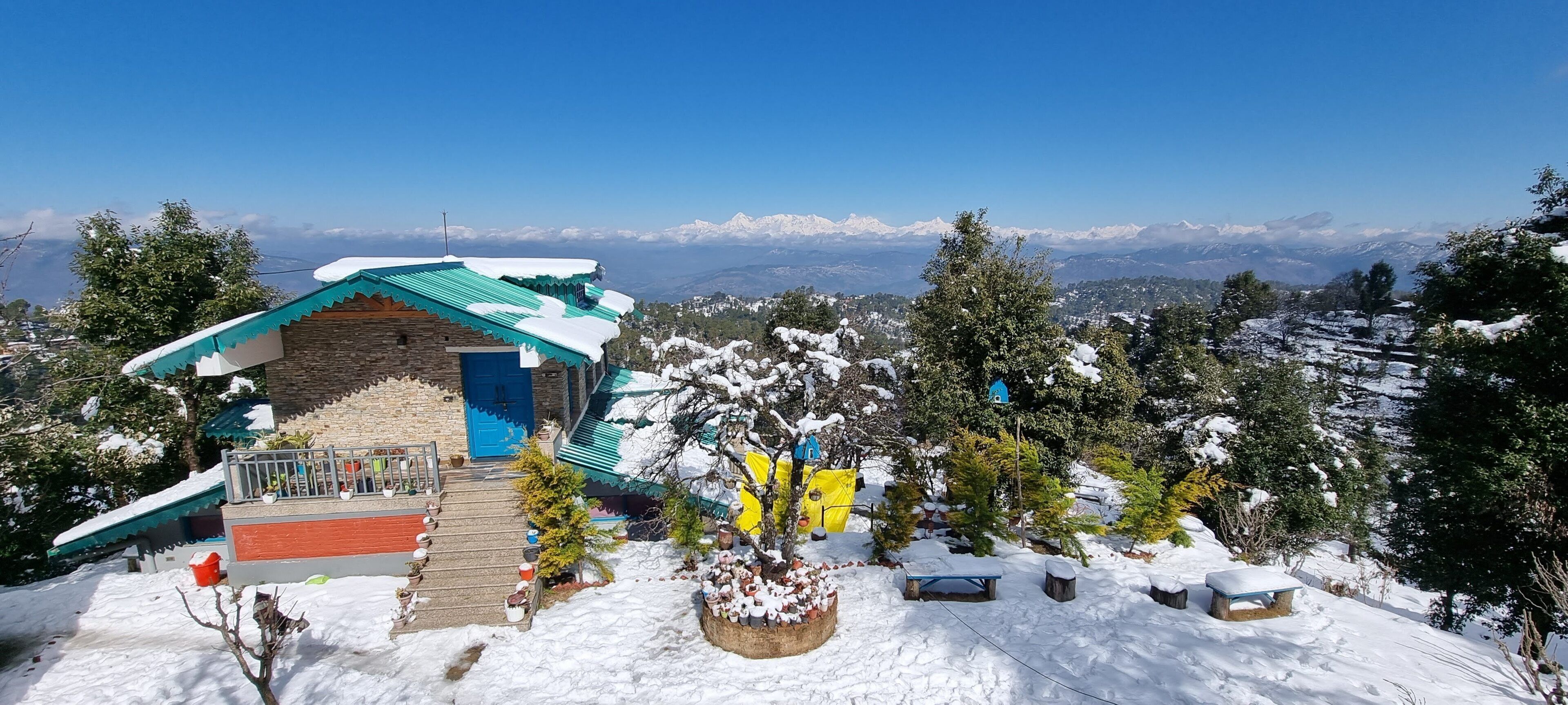 A mountain lodge with a stone facade, a blue door, and a green roof.