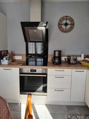 A modern kitchen with a built-in oven, a coffee maker, and a clock on the wall. - Country House (Yvecrique)