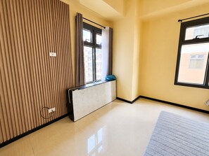 Una habitación con radiador, ventana con cortinas, cubierta para radiador y suelo de baldosas.