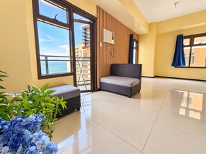 A spacious room with a large window, a sofa, a small table, and a potted plant. - Radiance Manila Bay · Pet-Friendly 100sqm 2BR (Pasay City)