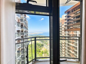 Un apartamento alto con balcón que da a un paisaje urbano y una masa de agua.