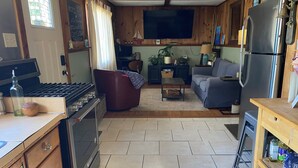 Eine kompakte Küche mit Herd, Backofen und Kühlschrank. Es gibt eine Essecke mit einer Couch und einem kleinen Tisch.