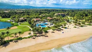 Ein Resort mit großem Pool, direkt am Strand und üppiger Bepflanzung.