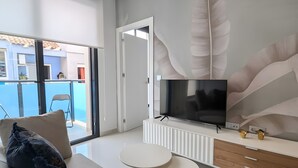 Een moderne woonkamer met een bank, een televisie, een witte dressoir en een groot raam.