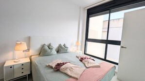 Een slaapkamer met een bed, twee nachtkastjes, een raam en een deur.
