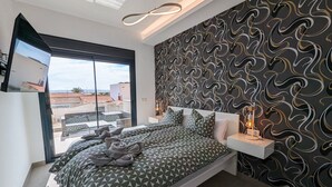 A modern bedroom with a large bed, a TV on the wall, and a patterned wallpaper.