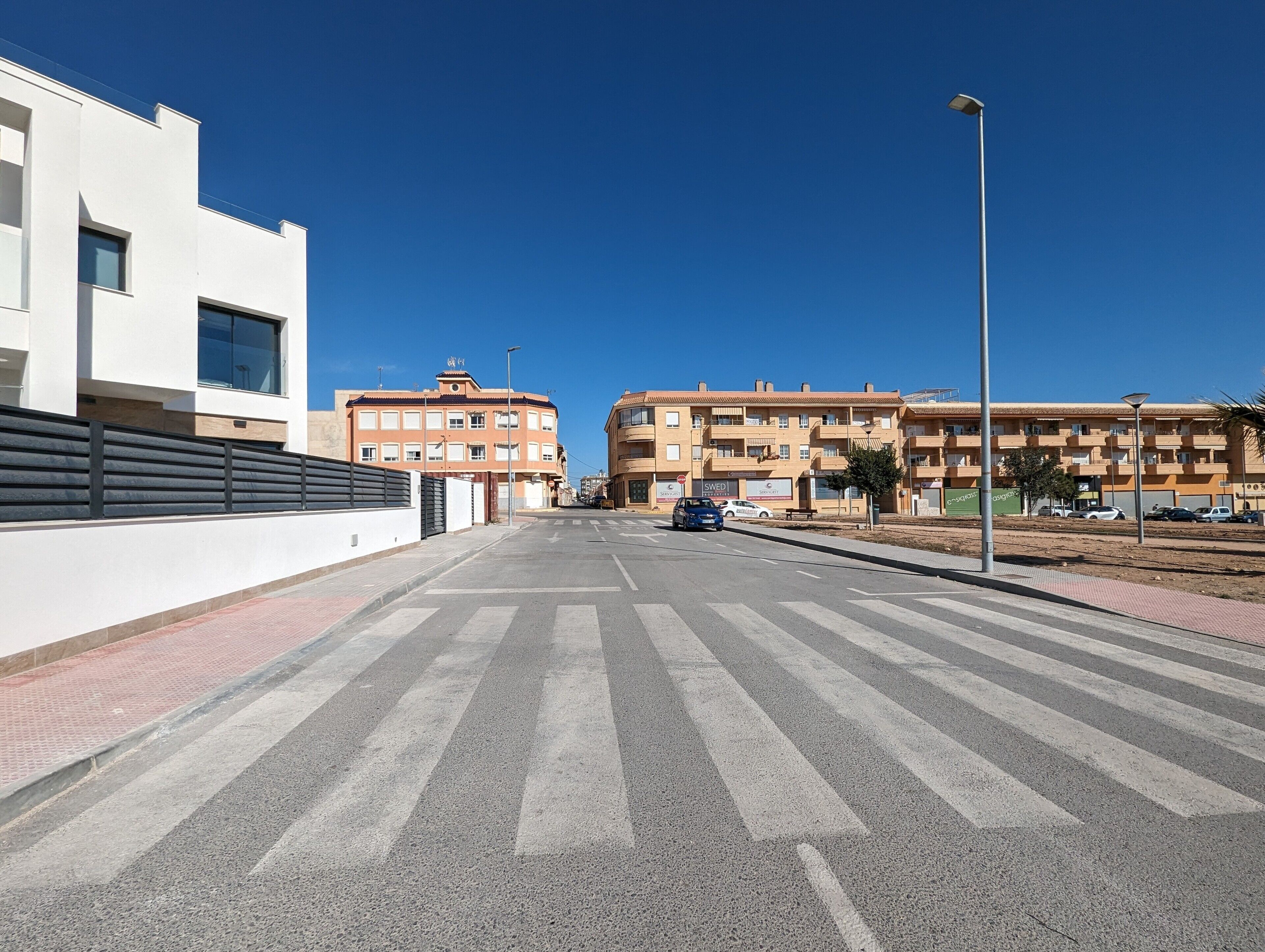 A wide pedestrian crossing with buildings on either side.