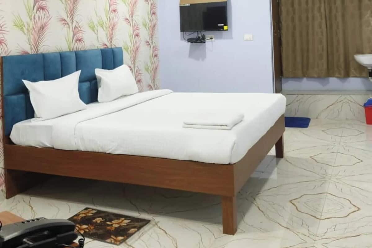 Un dormitorio con cama, ventilador de techo, televisor montado y aire acondicionado.