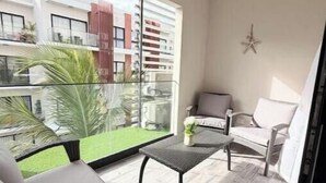 Uma varanda com vista para um edifício, uma cadeira, uma mesa pequena e uma decoração de estrela na parede.