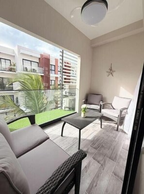 Ein Balkon mit Blick auf ein Gebäude, ein Stuhl, ein kleiner Tisch und eine Stern-Dekoration an der Wand.