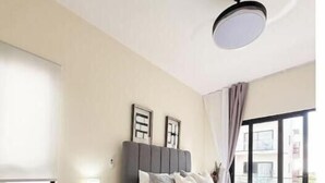Quarto com cama, sofá, mesa de cabeceira, abajur e luminária no teto.