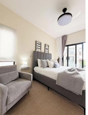 Ein Schlafzimmer mit einem Bett, einem Sofa, einem Nachttisch, einer Lampe und einer Deckenleuchte.