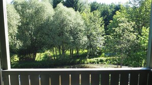A wooden deck with two metal chairs and a small round table.