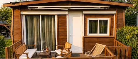 A wooden cabin with a deck, a sliding glass door, and a small window.