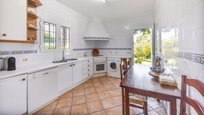 A kitchen with white cabinets, a dishwasher, a stove, a sink, and a window. - Villa Jacaranda Chiclana, Private Pool and Barbecue (Chiclana de la Frontera)