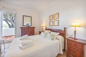 Une chambre à coucher comprenant un lit, deux tables de chevet, une commode, un miroir et des tableaux encadrés accrochés au mur.