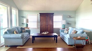 Uma sala de estar com dois sofás azul-claros, uma mesa de centro de madeira e um armário grande de madeira.