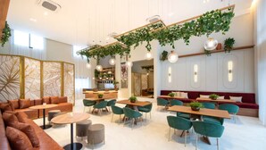 Interior moderno com área de estar, mesas e plantas penduradas.