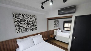 A hotel room with a bed, a bedside table, a mirror, and a wall-mounted air conditioning unit. - Studio Bem Localizado – Moema (São Paulo)