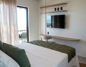 Una habitación de hotel con una cama, un televisor montado en la pared y una ventana con cortinas.