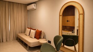 Una habitación moderna con sofá, una silla, una mesita y un espejo grande con marco de madera.
