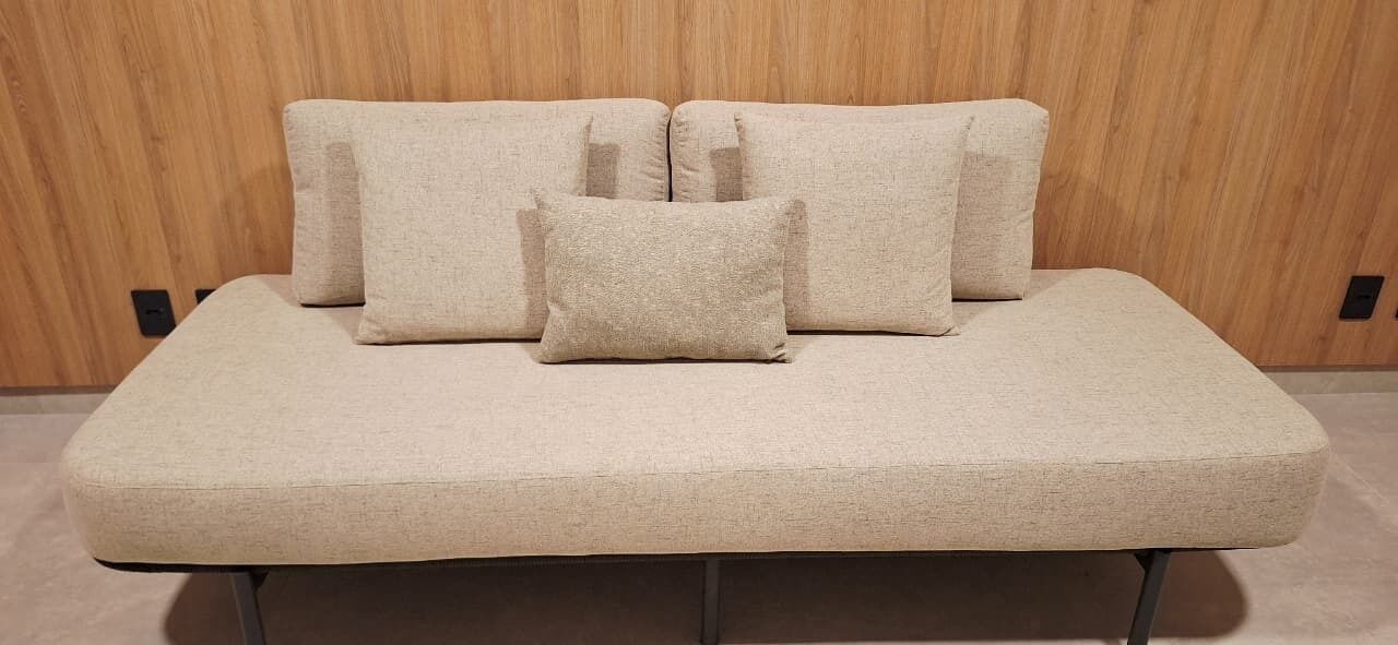 A sofa with four cushions against a wooden wall.