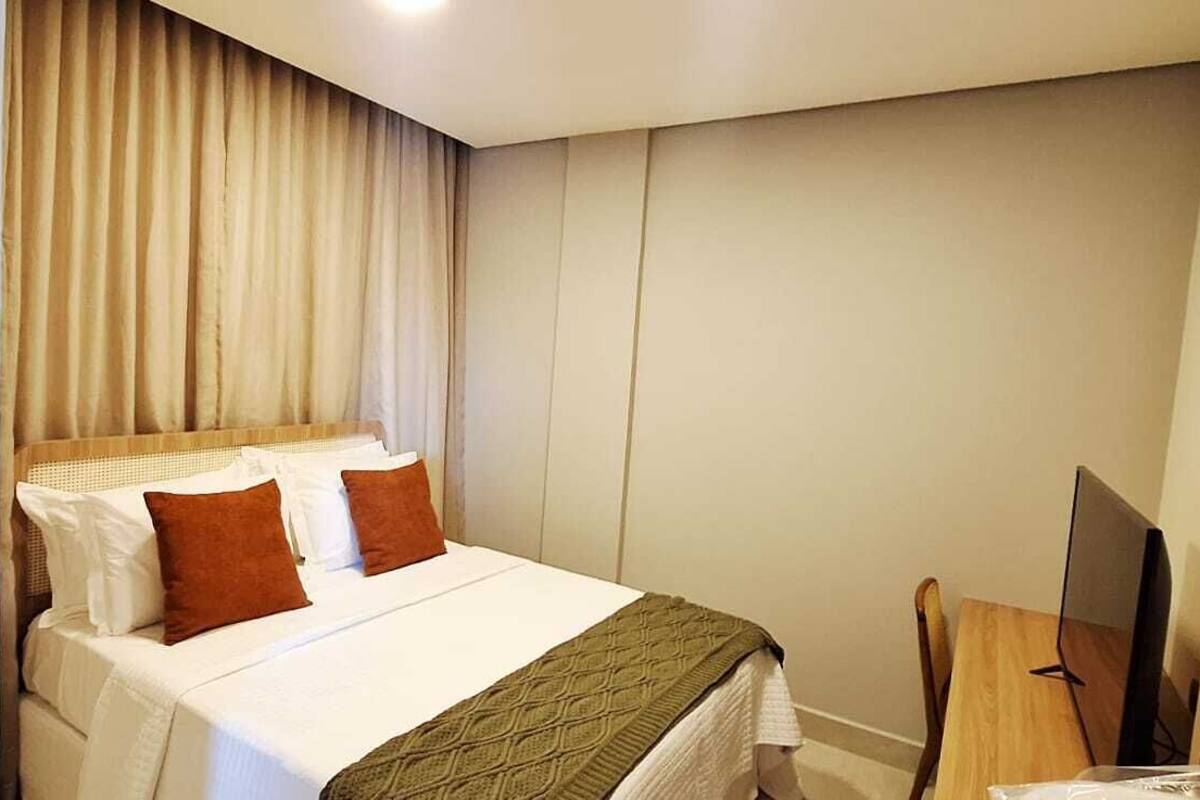 A hotel room with a bed, a television, and a curtain.