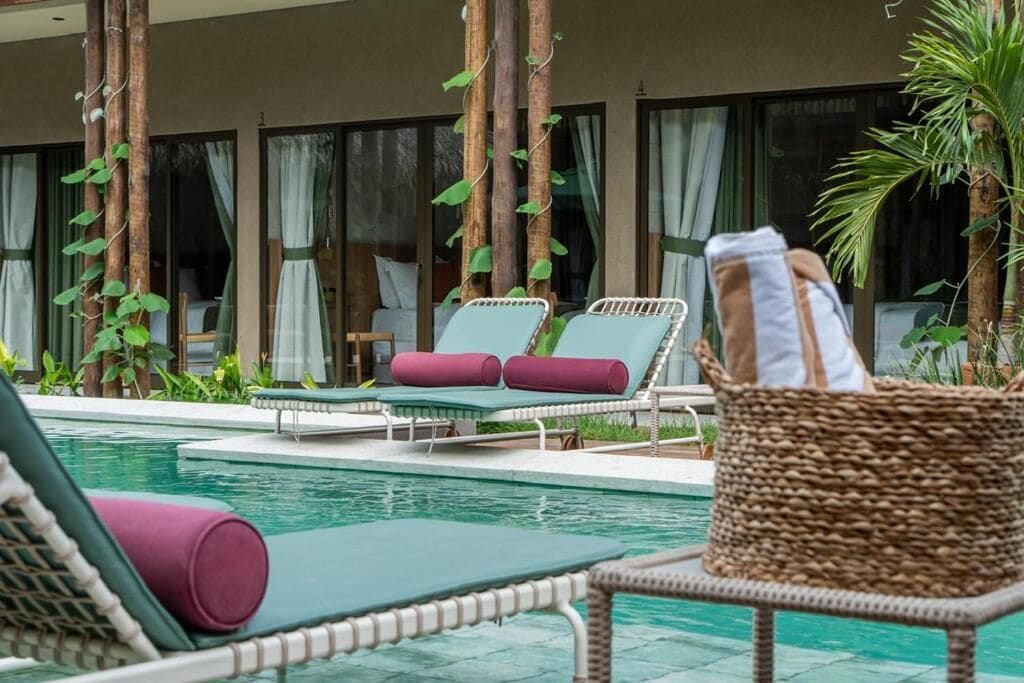 A poolside area with lounge chairs, a wicker basket, and a view of the building's interior.